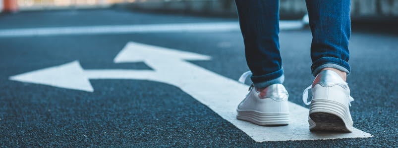 fötter som går på asfalt med pil ritad i asfalten.jpg
