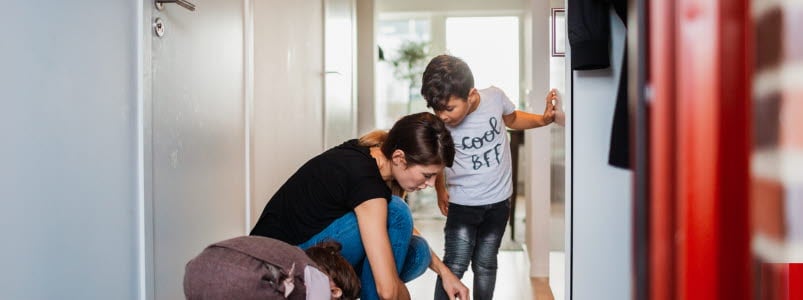 Mamma som hjälper sina barn på med skorna