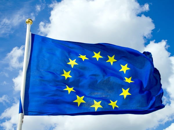 EU:s flagga som syns mot en molnig men solig himmel