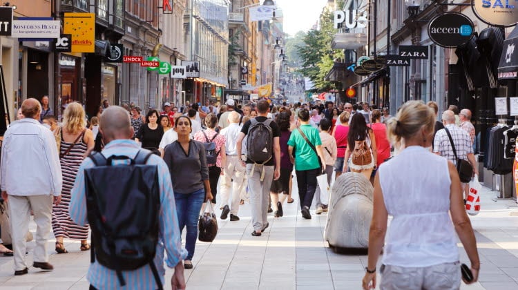 Sommardag på gågatan Drottninggatan mellan Mäster Samuelsgatan och Kungsgatan i Stockholm, Sverige, med folk i rörelse.